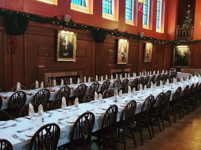 Long dining tables laid for a formal college dinner